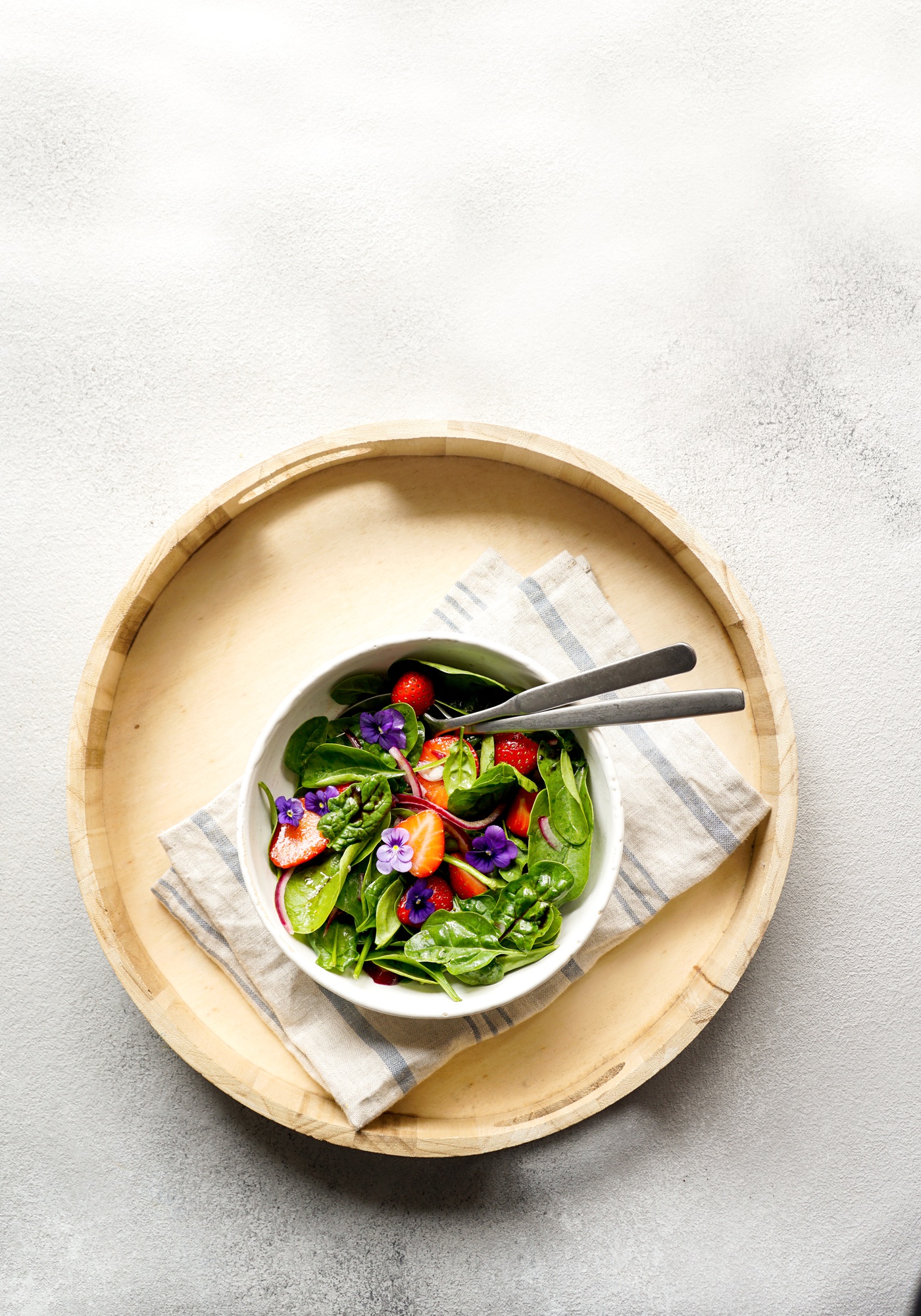 A tidy ceramic bowl with plated seasonal salad on wooden table